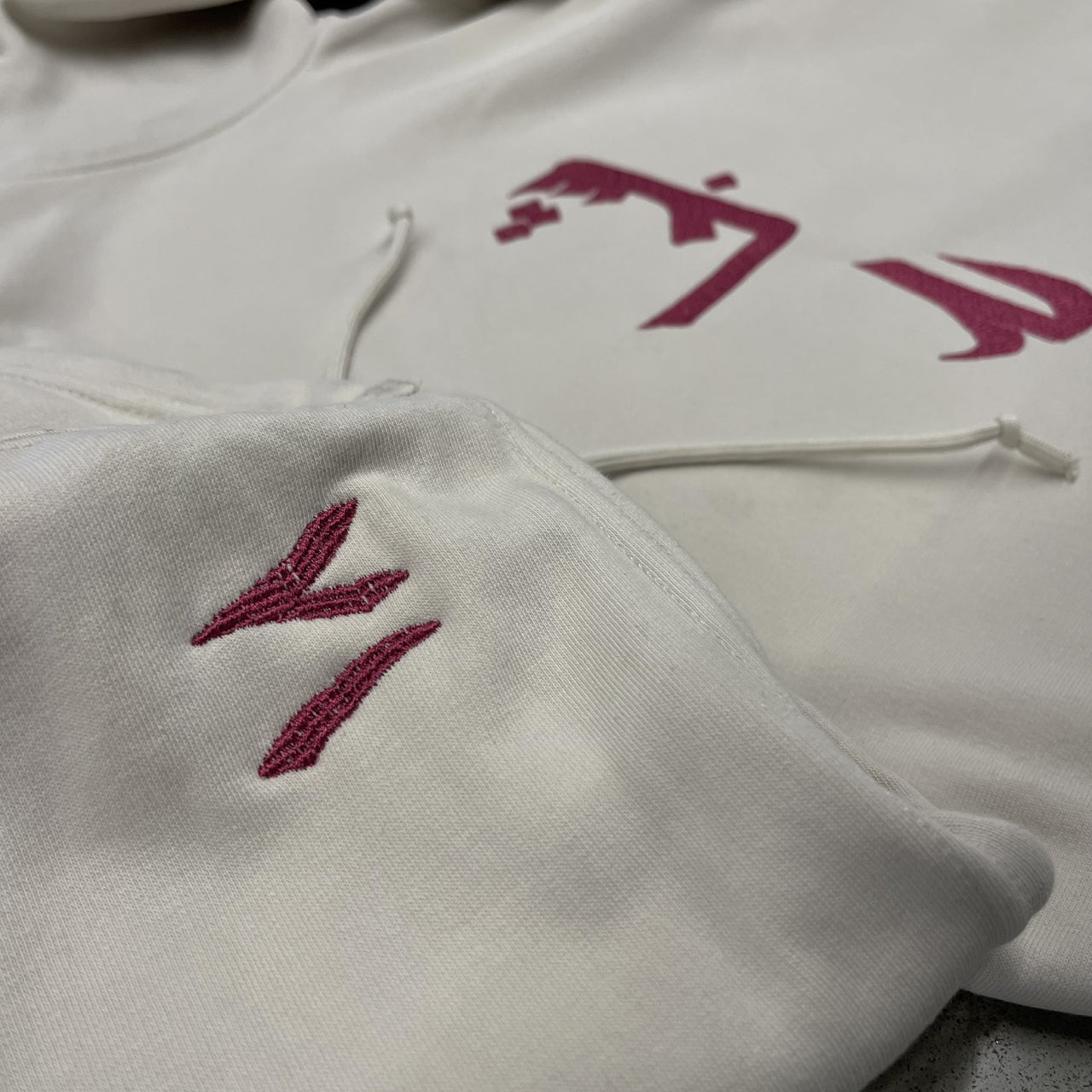 sweat à capuche blanc cassé et broderie rouge écriture arabe