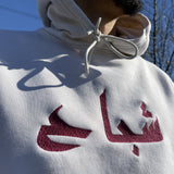 sweat à capuche blanc cassé et broderie rouge écriture arabe 